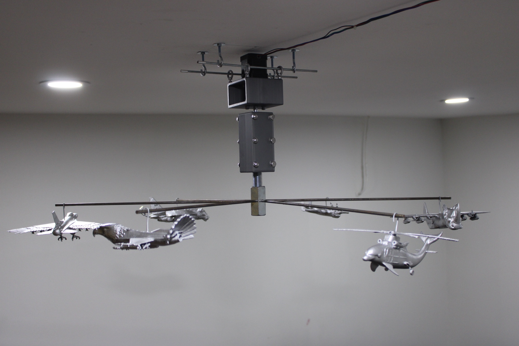 Mobilized, 2026 — installation view, plane-animal hybrids suspended from a rotating steel-wire mobile