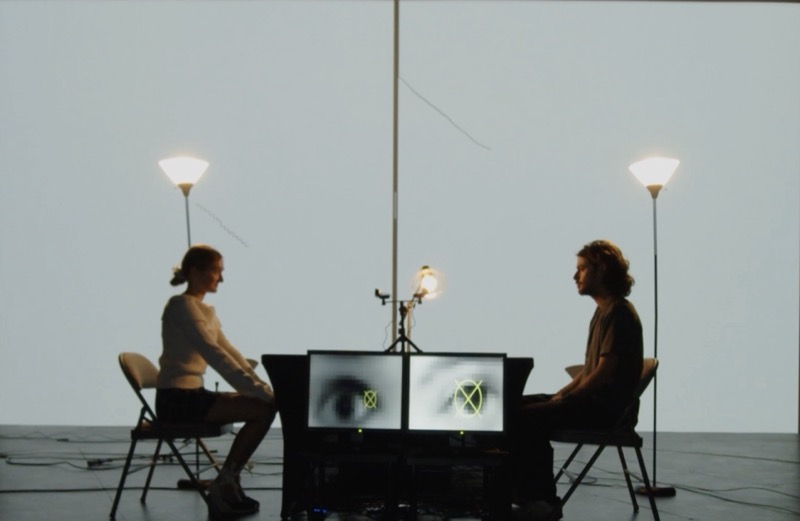 When We Are Two, 2023 — two performers holding eye contact across a dinner table, video and drawing behind them